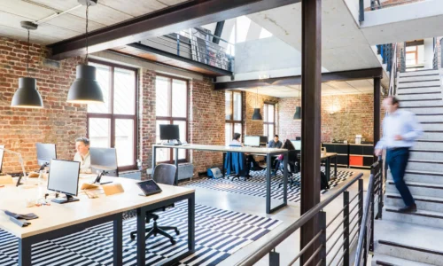 Bureaux en open space lumineux avec postes de travail et escalier