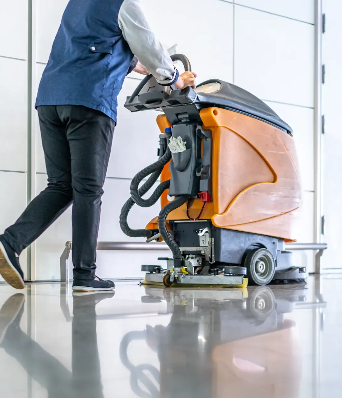 Préposé utilisant une grande machine de nettoyage au sol dans un espace intérieur.