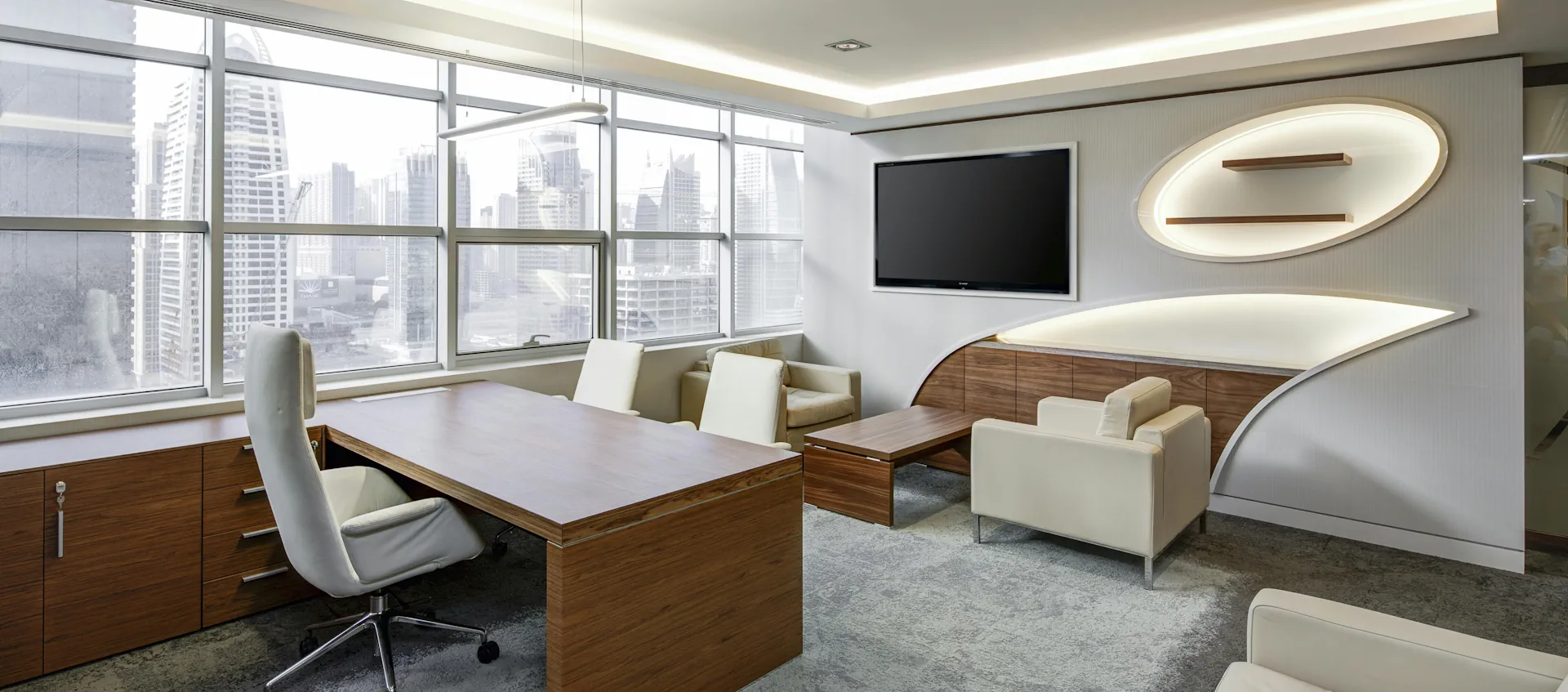 Salle de réunion élégante avec bureau, fauteuils et canapé dans un espace lumineux.
